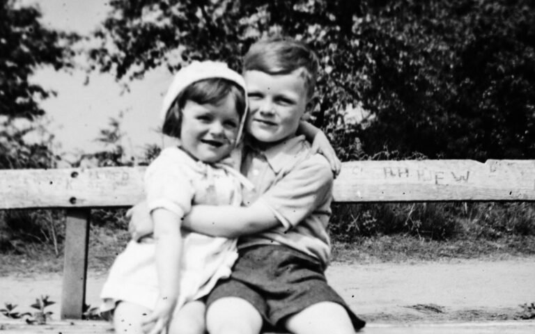 Image of two children from the 1950's sitting on a bench